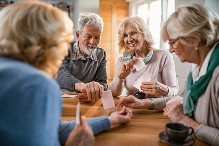 Happy seniors having fun while playing card game at home.